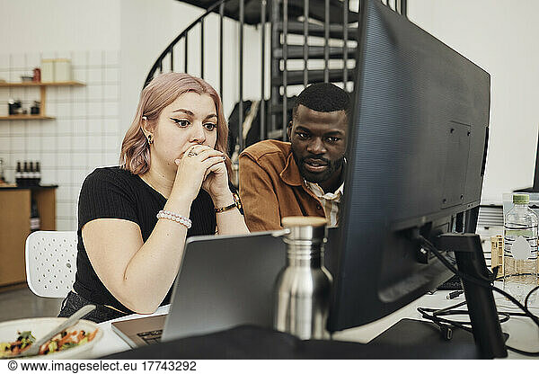 Male and female computer programmers looking at laptop in office