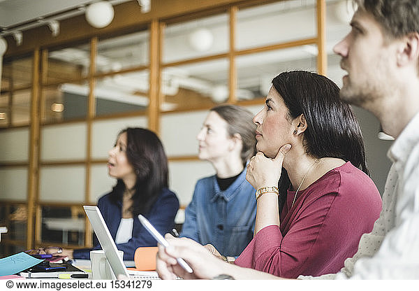 Male and female coworkers listening in meeting at board room
