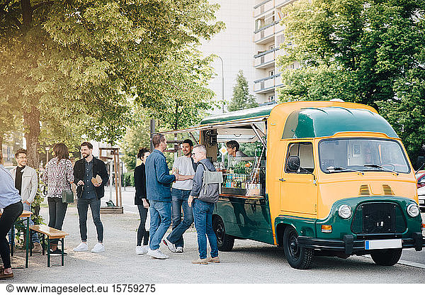 Male and female customers standing by food truck