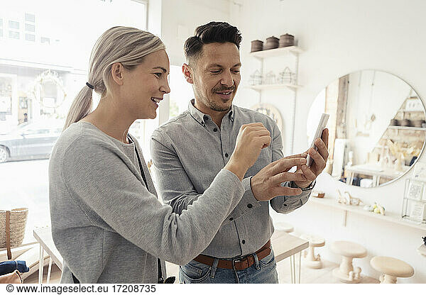 Male and female customers using smart phone in design studio