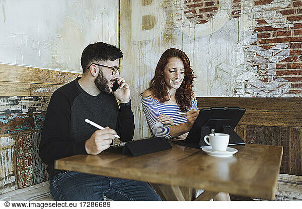 Male and female design professionals working at cafe