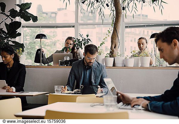 Male and female employees working at desk in coworking space