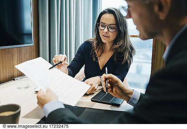 Male and female entrepreneur brainstorming over document during meeting in office
