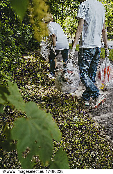 Male and female environmentalists picking up waste in park