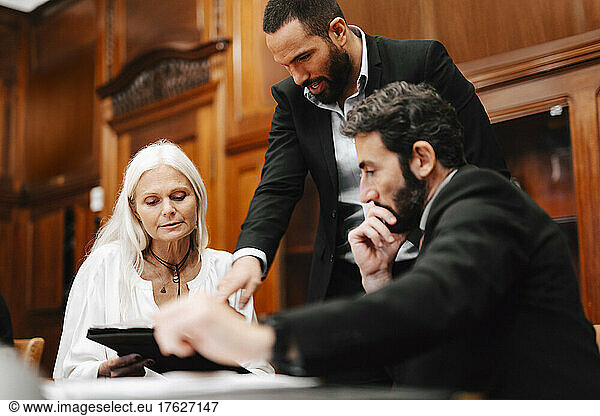 Male and female financial advisors brainstorming over document in meeting at office