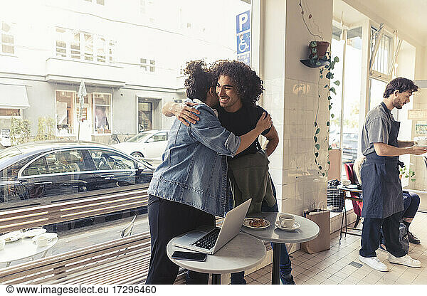 Male and female friends hugging each other at cafe