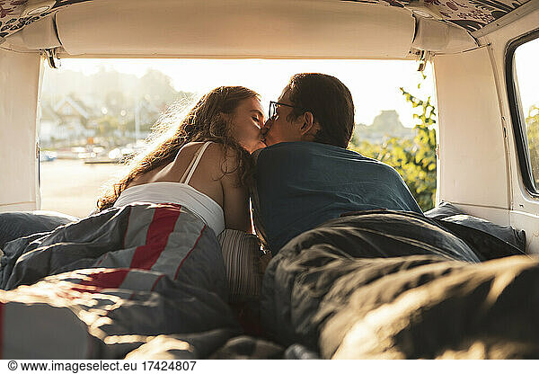 Male and female friends kissing each other in camping van