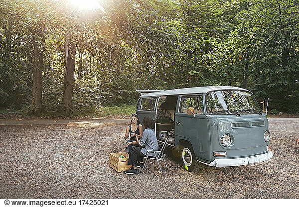 Male and female friends spending leisure time by camping van during vacation