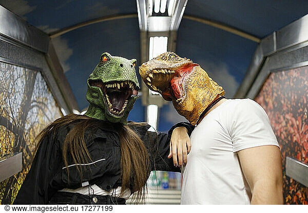 Male and female friends wearing dinosaur mask while traveling in train