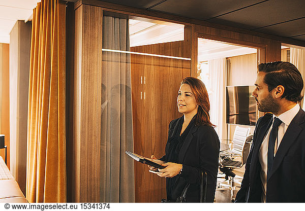 Male and female lawyers discussing while walking in office corridor