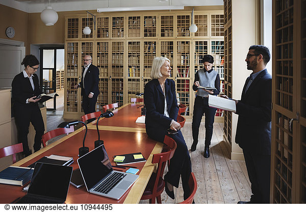 Male and female lawyers researching in board room at library