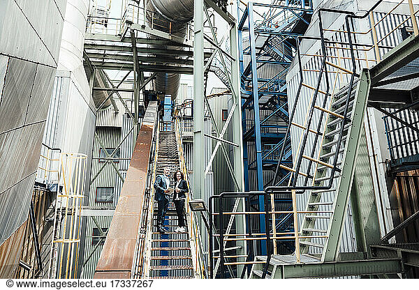 Male and female professionals standing on staircase at workshop