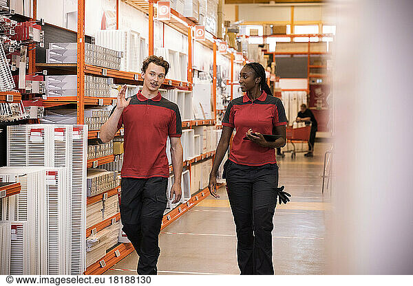 Male and female sales staff talking while walking in hardware store