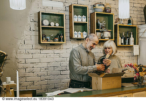 Male and female senior owners unpacking merchandise at home decor shop