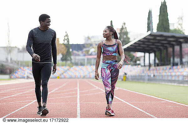 Male and female sportsperson walking on track against clear sky
