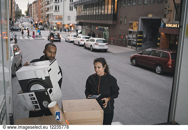 Male and female workers are stacking cardboard boxes in delivery van