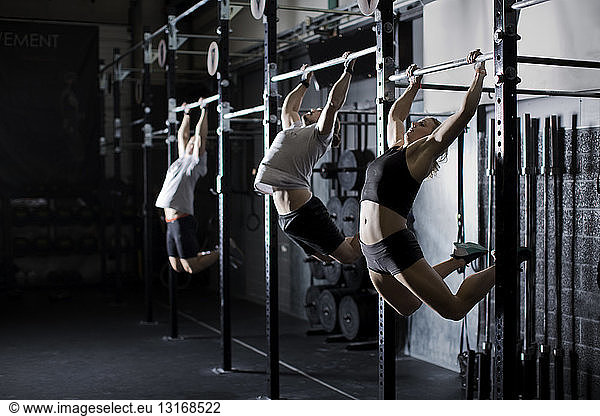 Male and female young adults training on wall bar in gym