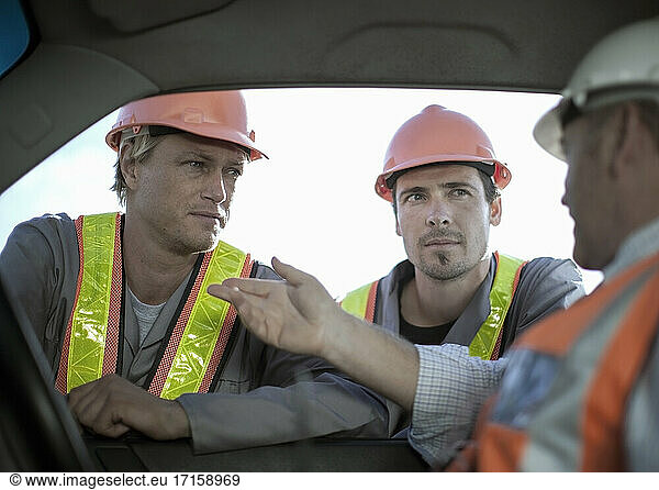 Male architect explaining construction workers while sitting in truck