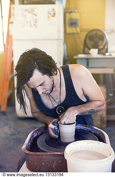 Male artist molding bowl at workshop