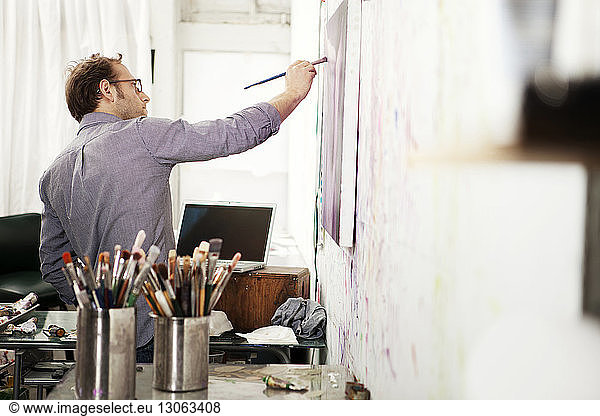 Male artist painting on canvas in studio