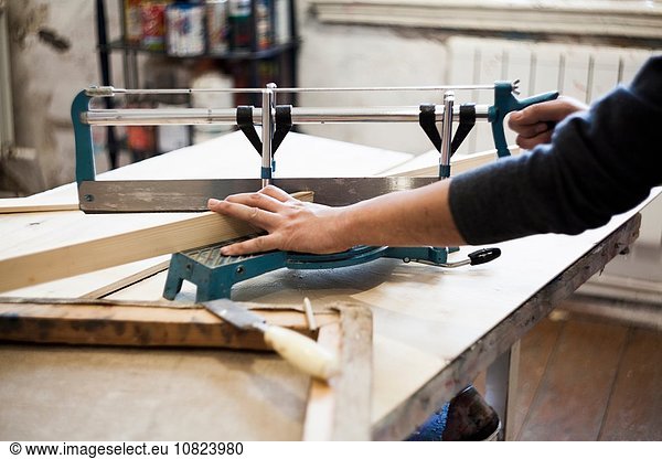 Male artist  sawing wood  making frame for artwork