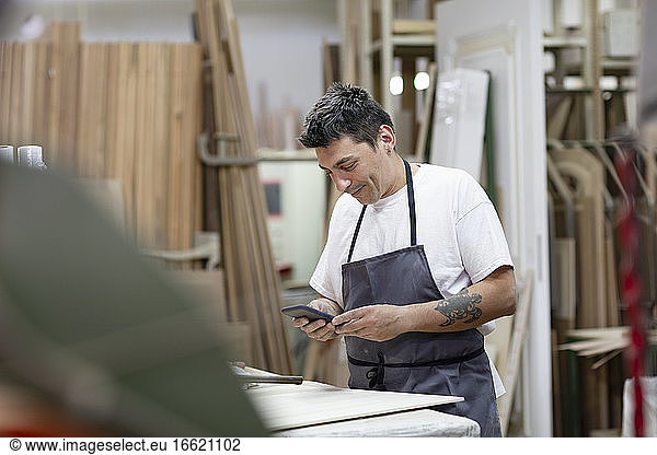 Male artist using mobile phone while standing at workshop
