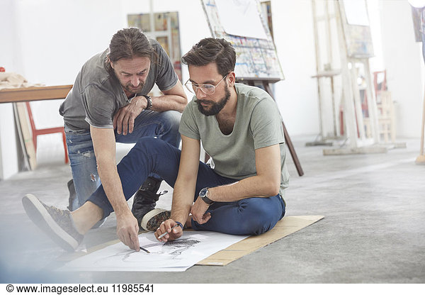 Male artists sketching on floor in art class studio