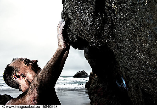 male athlete bouldering on coast rocks