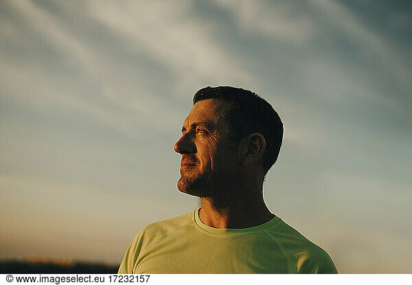 Male athlete contemplating against sky during sunset