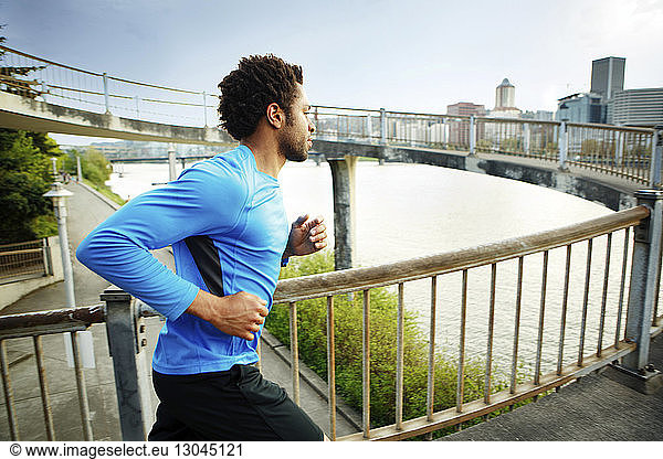 Male athlete jogging on bridge in city