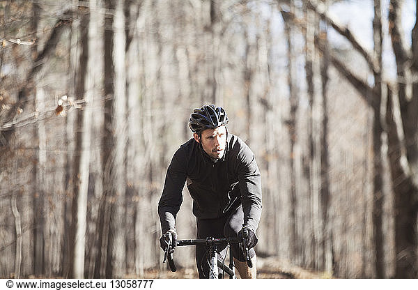 Male athlete riding bicycle on road in forest