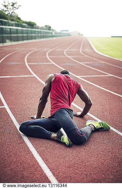 Male athlete stretching on running tracks