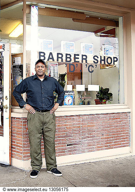 Male barber standing against hair salon