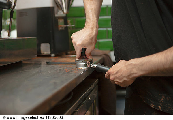 Male barista's hands preparing coffee machine in cafe