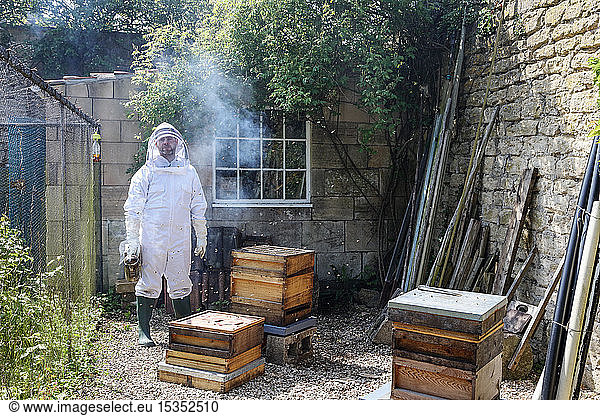 Male beekeeper carrying bee smoker in walled garden  portrait