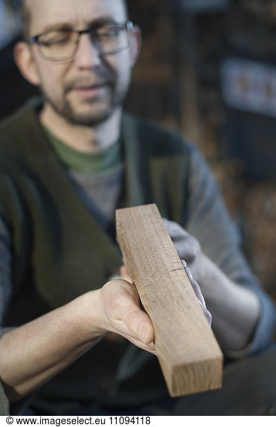 Male bow maker checking quality of wood in workshop  Bavaria  Germany