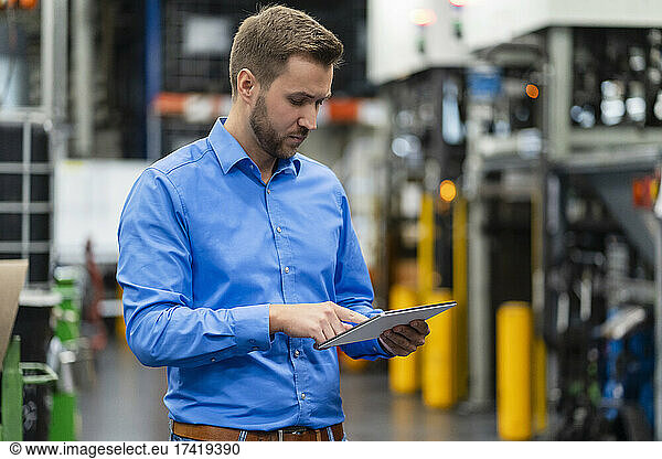 Male business professional using digital tablet in factory