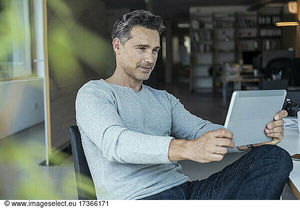 Male business professional using digital tablet while working at office