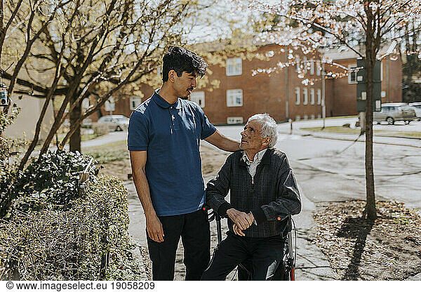 Male caregiver with hand on shoulder of senior man sitting on walker