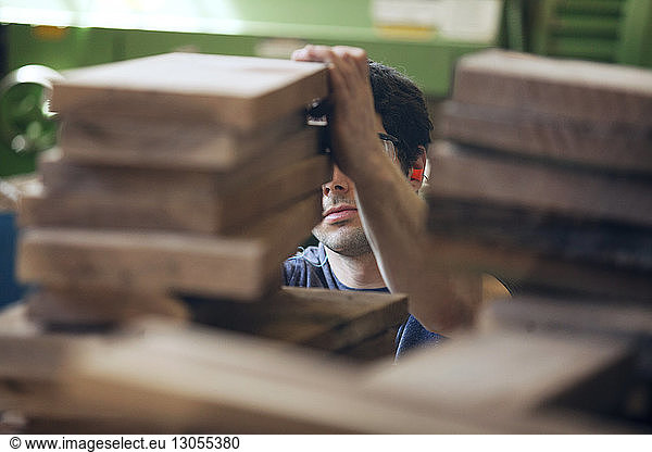 Male carpenter examining wooden planks in workshop