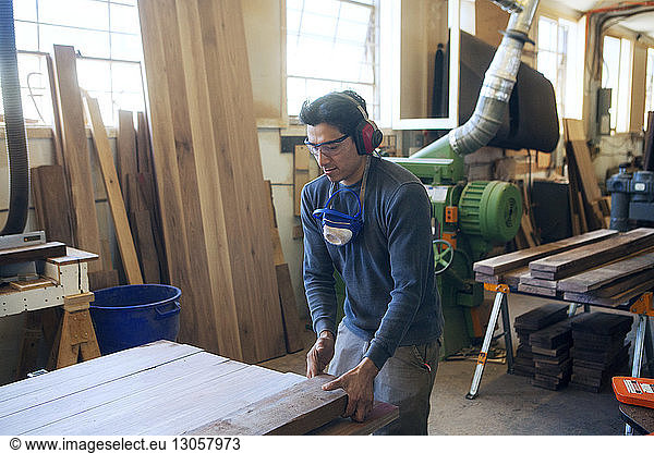 Male carpenter holding wooden plank at workshop