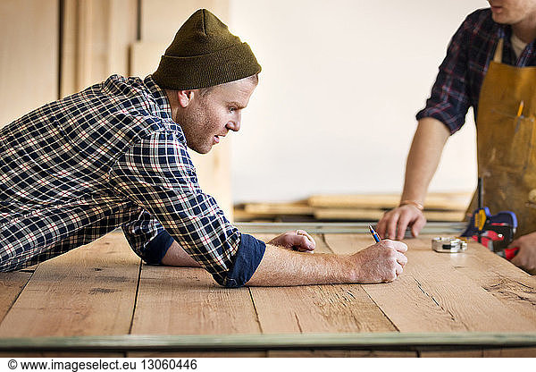 Male carpenter marking on wood at workshop