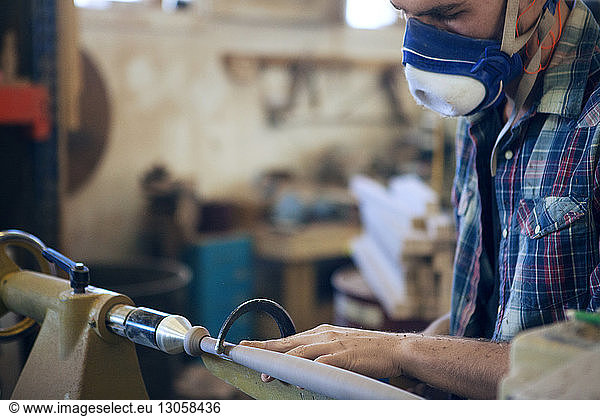 Male carpenter using handsaw in workshop