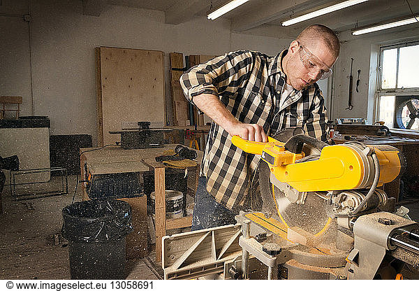 Male carpenter using machinery in workshop