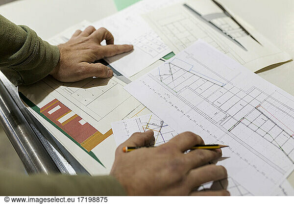 Male carpenter with paperwork at workbench in industry