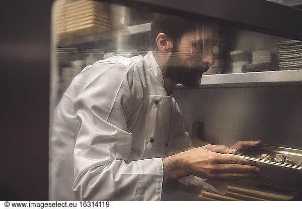 Male chef baking mushroom in commercial kitchen