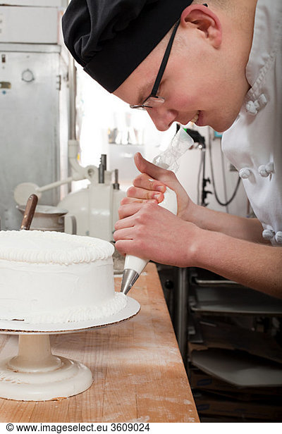 Male chef icing a cake in commercial kitchen