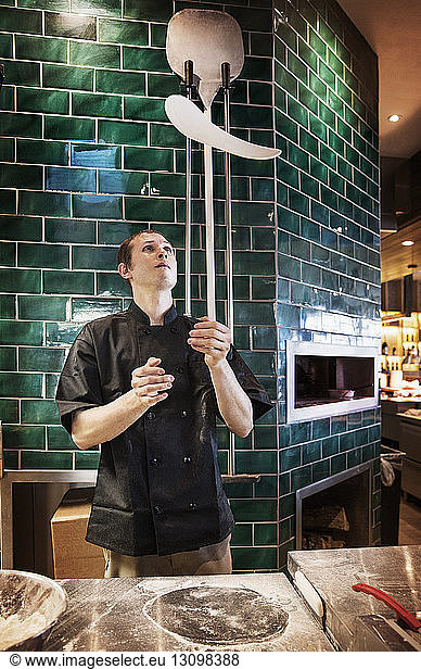 Male chef tossing pizza dough in commercial kitchen
