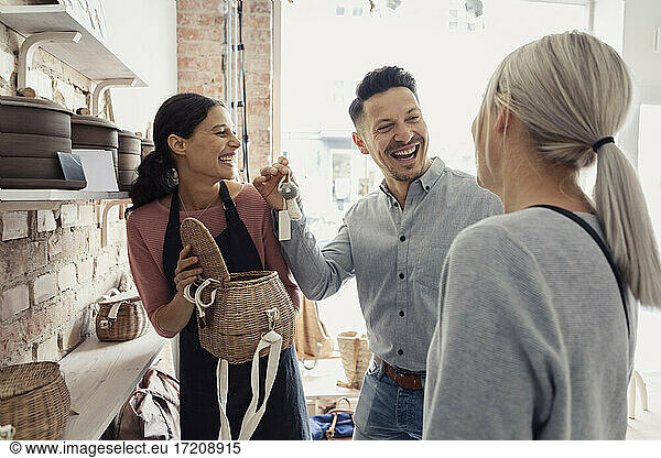 Male client laughing while standing by female owner in design studio