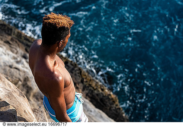 Male cliff diver looking at the ocean jump zone before diving in oahu